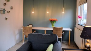 A room with a dark blue accent wall, a dining table with two chairs, a sofa, a lamp, and wall-mounted birdhouse decorations. - Cozy Holiday Home in Noordwijkerhout near Lake (Noordwijkerhout)