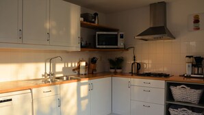 A modern kitchen with white cabinets, a stainless steel microwave, a gas stove, and a sink. - Cozy Holiday Home in Noordwijkerhout near Lake (Noordwijkerhout)