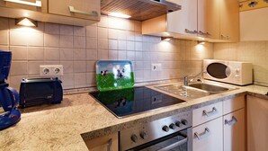 Een moderne keuken met een roestvrijstalen fornuis, een magnetron en een spoelbak. Er zijn houten kastjes en een betegelde achterwand.