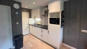 A compact kitchen with white cabinets, a black countertop, a microwave, and a gas stove.