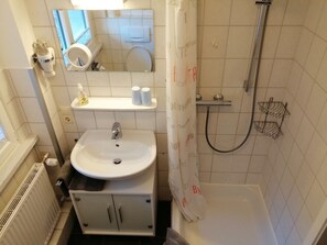 A bathroom with a sink, mirror, toilet, shower, and a towel rack. - Pretty Apartment in Oppenau near Black Forest National Park (Oppenau)