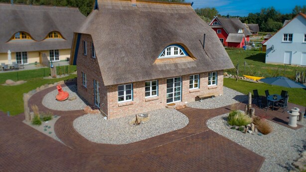 A house with a steeply pitched roof, brick exterior, and a gravel driveway. - Exklusives Reetdachhaus mit Sauna in Rerik (Rerik)