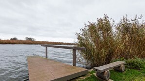 Eine Holzstege führt ins Wasser, mit einer Bank und einem Geländer entlang der Seite.