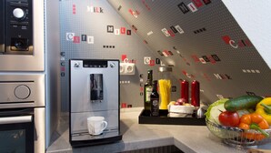 A kitchen with a coffee machine, a bowl of fruit, and a wall with 'Cafe' and 'Milk' logos. - Wohnung in Hoxter Nahe Schloss Corvey (Hoexter)