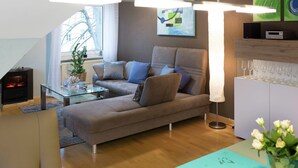 A modern living room with a sofa, a glass coffee table, a fireplace, and a view of a tree through a window. - Wohnung in Hoxter Nahe Schloss Corvey (Hoexter)