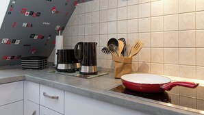 A kitchen with white cabinets, a coffee maker, a red frying pan, and a utensil holder. - Wohnung in Hoxter Nahe Schloss Corvey (Hoexter)