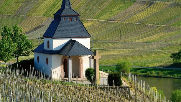 A small church with a pointed steeple, surrounded by terraced vineyards and a river. - Apartment in Trittenheim With Terrace and Garden (Trittenheim)