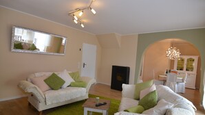A living room with two white sofas, a green rug, a coffee table, and a fireplace. - Wonderful Apartment With Barrel Sauna (Stockheim)