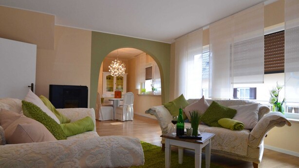 A living room with two sofas, a coffee table, and a fireplace. There is a kitchen in the background with a dining table and chairs. - Wonderful Apartment With Barrel Sauna (Stockheim)