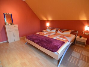 Ein Schlafzimmer mit Bett, Nachttischen, einem Schminktisch und einem Spiegel.