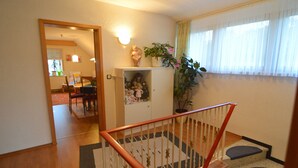 A staircase with a wooden handrail and a patterned rug leading to a dining area with a table and chairs. - Cozy Apartment in Neumagen-Dhron near Lake Mosel with Garden (Neumagen-Dhron)