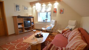 A cozy living room with a sofa, a coffee table, a TV, and a bookshelf. - Cozy Apartment in Neumagen-Dhron near Lake Mosel with Garden (Neumagen-Dhron)