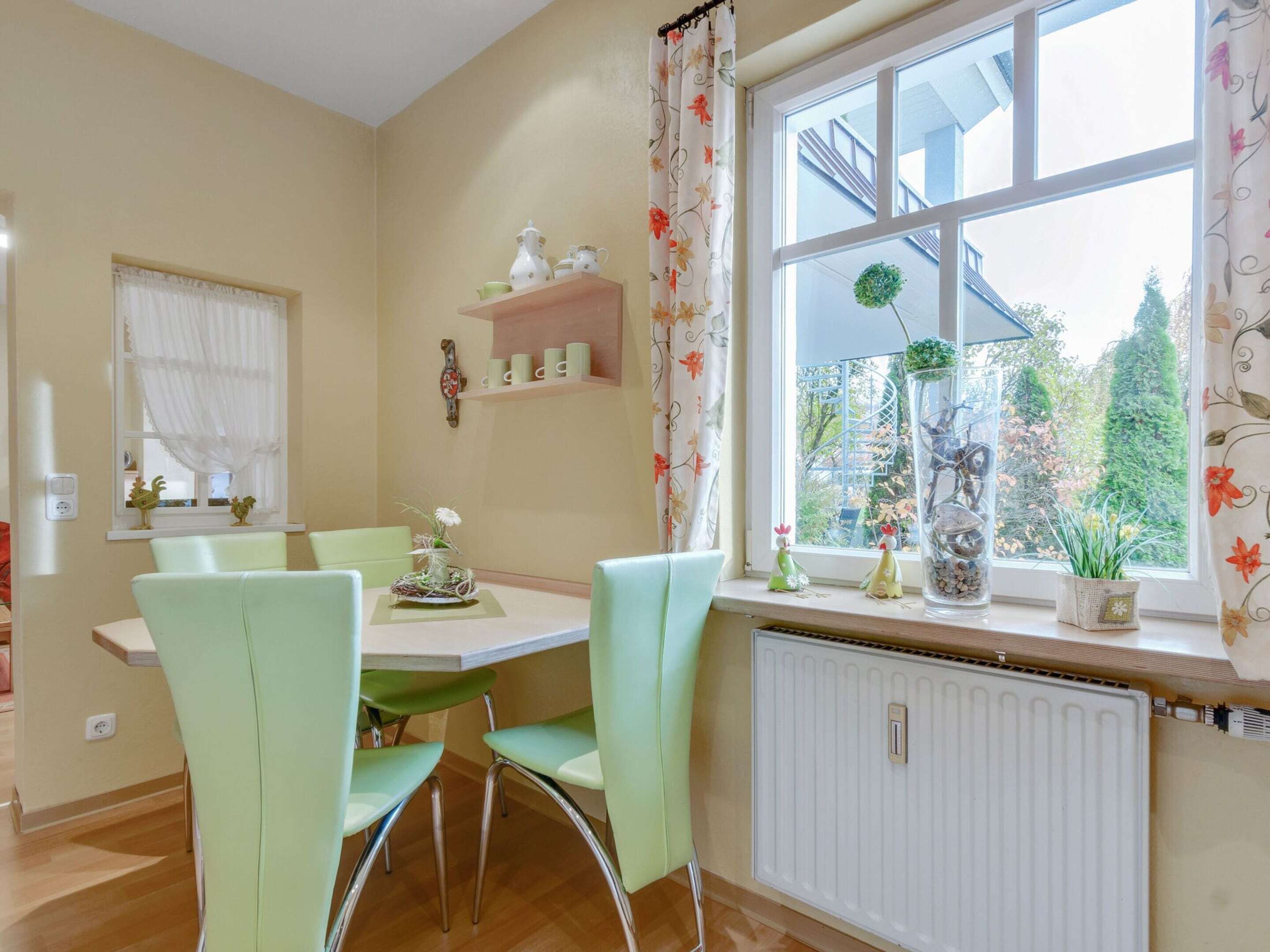 A dining area with a table and chairs, a window with a view, and a radiator.