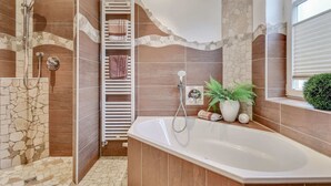A modern bathroom with a freestanding bathtub, a shower area, and a towel rack.