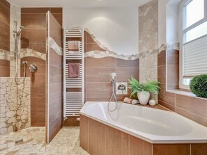 A modern bathroom with a freestanding bathtub, a shower area, and a towel rack.