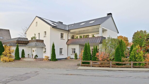 A modern two-story house with a sloped roof, a front porch, and a driveway.