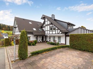 A traditional half-timbered house with a sloped roof, a front porch, and a paved driveway. - Apartment on the Edge of the Forest (Eslohe)