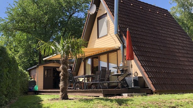 A house with a sloped roof, a satellite dish, and a patio with outdoor furniture. - Pure nature - forest vacation in the Tiny House (Ronshausen)