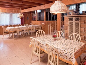 Un espace repas avec des tables et des chaises en bois, un luminaire suspendu et un mur en briques.