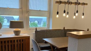 Un coin repas chaleureux avec une table et un banc en bois, une lampe et un luminaire fixé au mur.