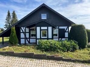 A black and white half-timbered house with a pitched roof, a small window at the top, and a covered porch area. - Detached Holiday Home in Sauerland near Winterberg with Terrace & Garden (Winterberg)