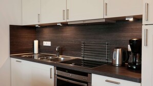 Une cuisine moderne avec des armoires blanches, des appareils en acier inoxydable et un pare-feu en bois foncé.