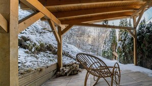 A wooden pergola with a rocking chair, snow-covered ground, and a view of a snowy landscape. - Large Holiday Home near Winterberg with Garden, Terrace, & Garage (Winterberg)