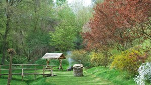 A rustic outdoor setting with a wooden structure, a stone barbecue, and a wooden fence. - Relaxing Watermill Hideaway (Heringen)