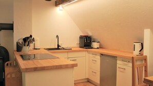 A compact kitchen with a wooden countertop, a sink, a coffee maker, and a dishwasher. - Relaxing Watermill Hideaway (Heringen)