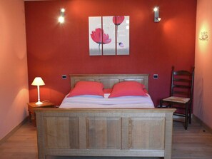 A bedroom with a wooden bed, red walls, a nightstand with a lamp, and a chair. - Stylish Holiday Home in Han-sur-lesse With Terrace (Rochefort)