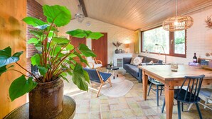 A cozy room with a wooden ceiling, a dining table, chairs, a sofa, and a large potted plant. - Holiday Home in Zorgvlied Near Drents (Zorgvlied)