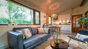 A cozy living room with a leather sofa, a dining table, and a kitchen in the background. - Holiday Home in Zorgvlied Near Drents (Zorgvlied)