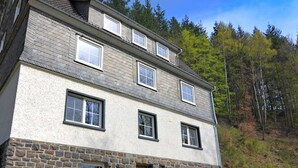 A two-story stone building with multiple windows, a wooden door, and a stone staircase leading to the entrance. - Lovely Group House near Winterberg with Private Sauna, Garden, & Terrace (Hallenberg)