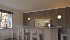 A bar area with a wooden counter, a large mirror, and two wall-mounted lamps. - Lovely Group House near Winterberg with Private Sauna, Garden, & Terrace (Hallenberg)