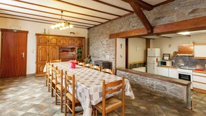 A spacious kitchen with a stone wall, wooden cabinets, and a tiled floor. - Holiday Home in Bastogne With Garden (Bastogne)
