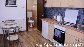 Une cuisine compacte avec des meubles en bois, une cuisinière à gaz, un lave-vaisselle et un petit coin repas comprenant une table et des chaises.