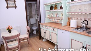 Une cuisine équipée d’une cuisinière, d’un évier et de placards. On y trouve une chaise et une table sur laquelle est posé un vase de fleurs.