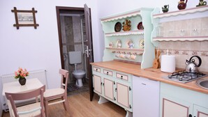 A kitchen with a stove, sink, and cabinets. There is a chair and a table with a vase of flowers.
