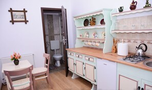 A kitchen with a stove, sink, and cabinets. There is a chair and a table with a vase of flowers.