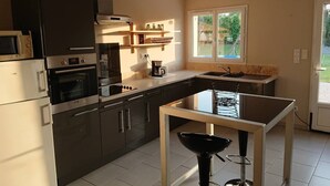 Una cucina moderna con mobili scuri, forno integrato, microonde e macchina da caffè.