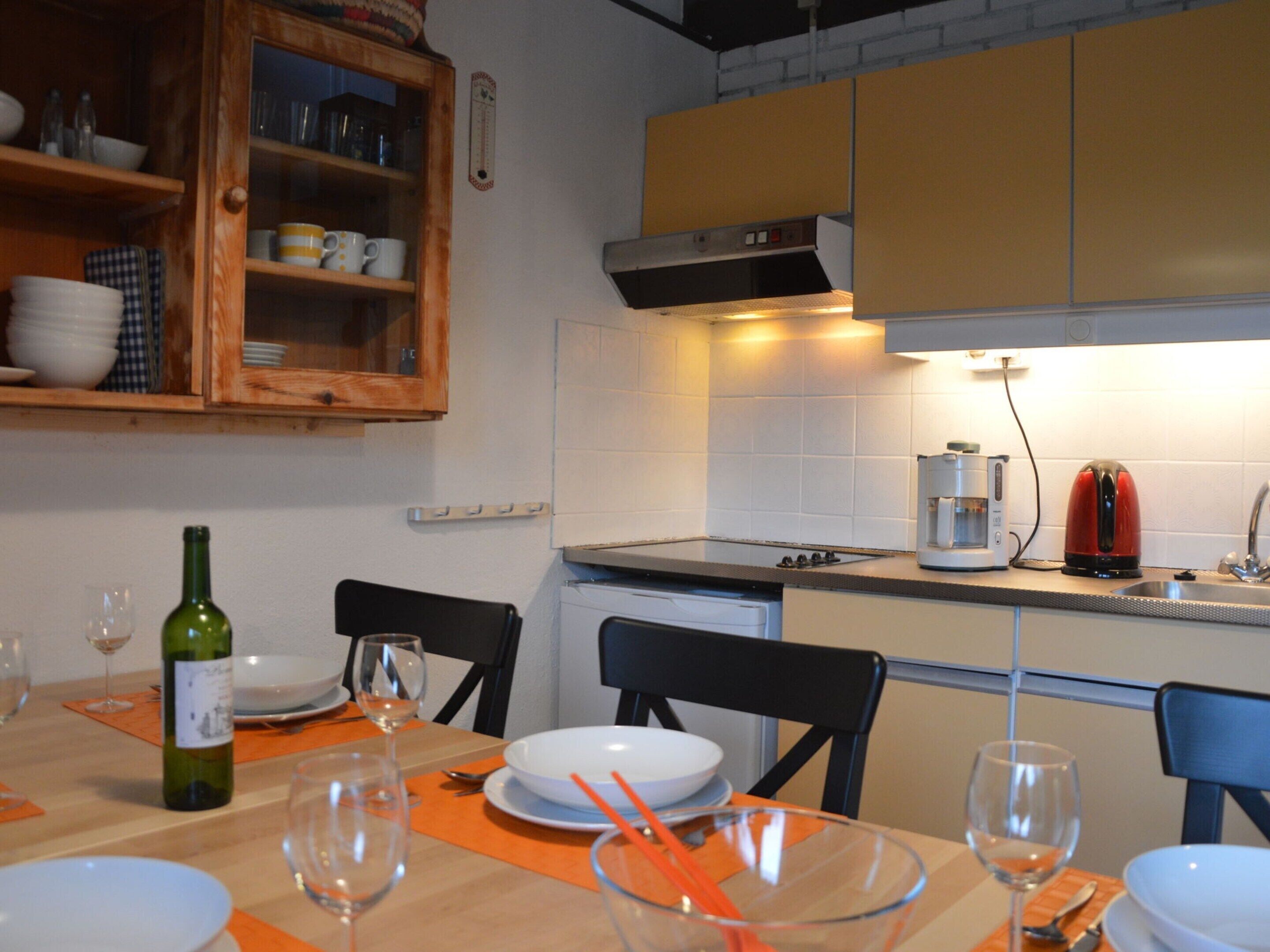 Una cocina con una mesa de comedor para cuatro personas, una cafetera y un hervidor.