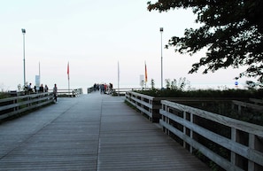 A wooden boardwalk leading to a body of water, flanked by railings and flags. - Cozy Apartment in Boltenhagen Germany near Beach (Boltenhagen)