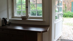 A kitchen with a window overlooking a garden, a wooden countertop, and a basket on the windowsill. - Ferienwohnung in Reddelich for 4 Personen (Reddelich)
