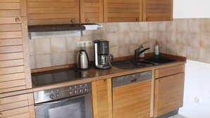 A kitchen with wooden cabinets, a Bosch dishwasher, a coffee maker, and a kettle. - Ferienwohnung in Reddelich for 4 Personen (Reddelich)
