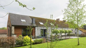 Uma casa moderna com telhado inclinado, paredes de pedra e um gramado bem cuidado.