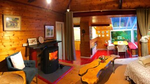 Ein gemütliches Blockhaus-Interieur mit Kamin, Holzwänden, Essbereich und einem Bett.
