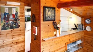 Ein Holzblockhaus-Interieur mit Küchenbereich, Holzwänden, einem Gemälde und einem kleinen Esstisch.