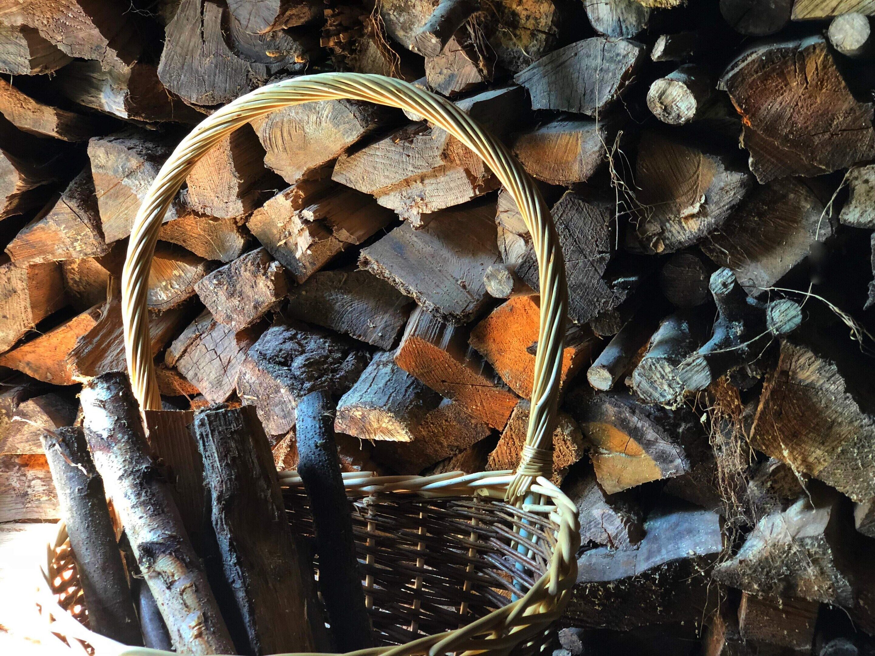 Een rieten mand gevuld met hout, geplaatst op een stap houtblokken.