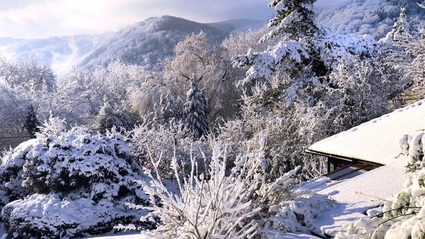 Schneebedeckte Landschaft mit einem Gebäude und einem geneigten Dach.