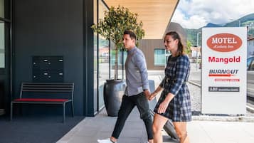 A couple walking towards a building with a sign for 'Motel Keckeiis Inn Mangold'.